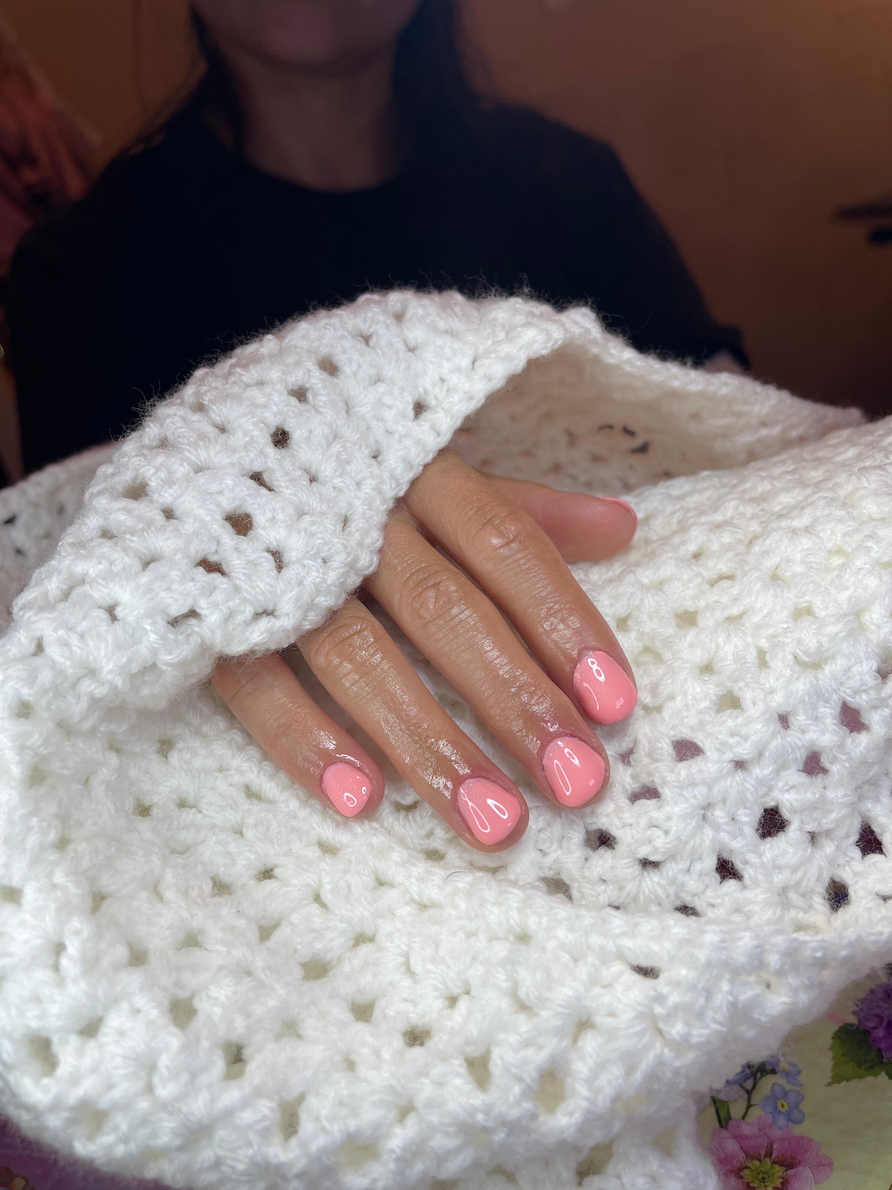 Coral manicure resting on handmade crochet